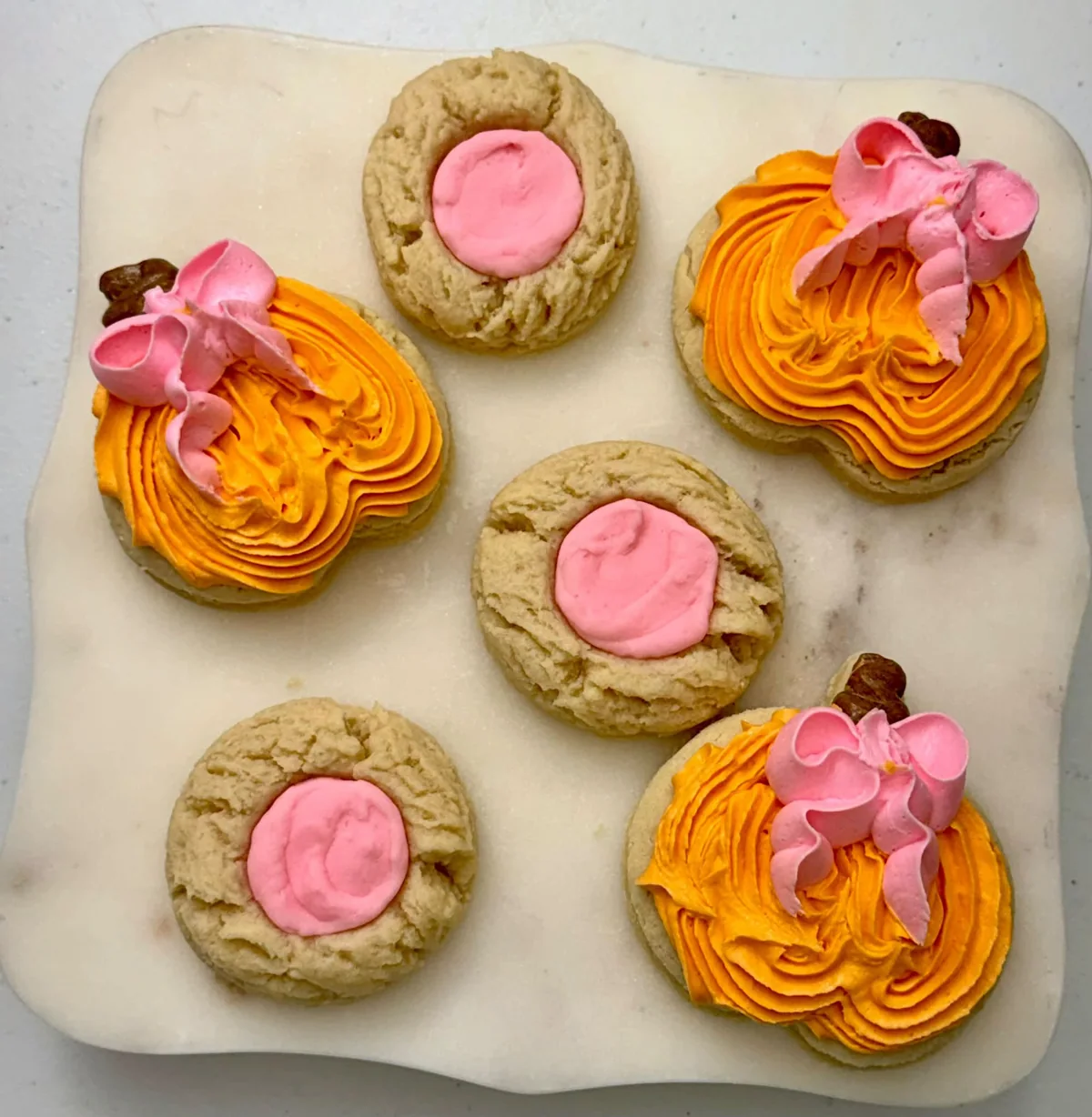 Pumpkin cookies with pink frosting bows, made by Laura